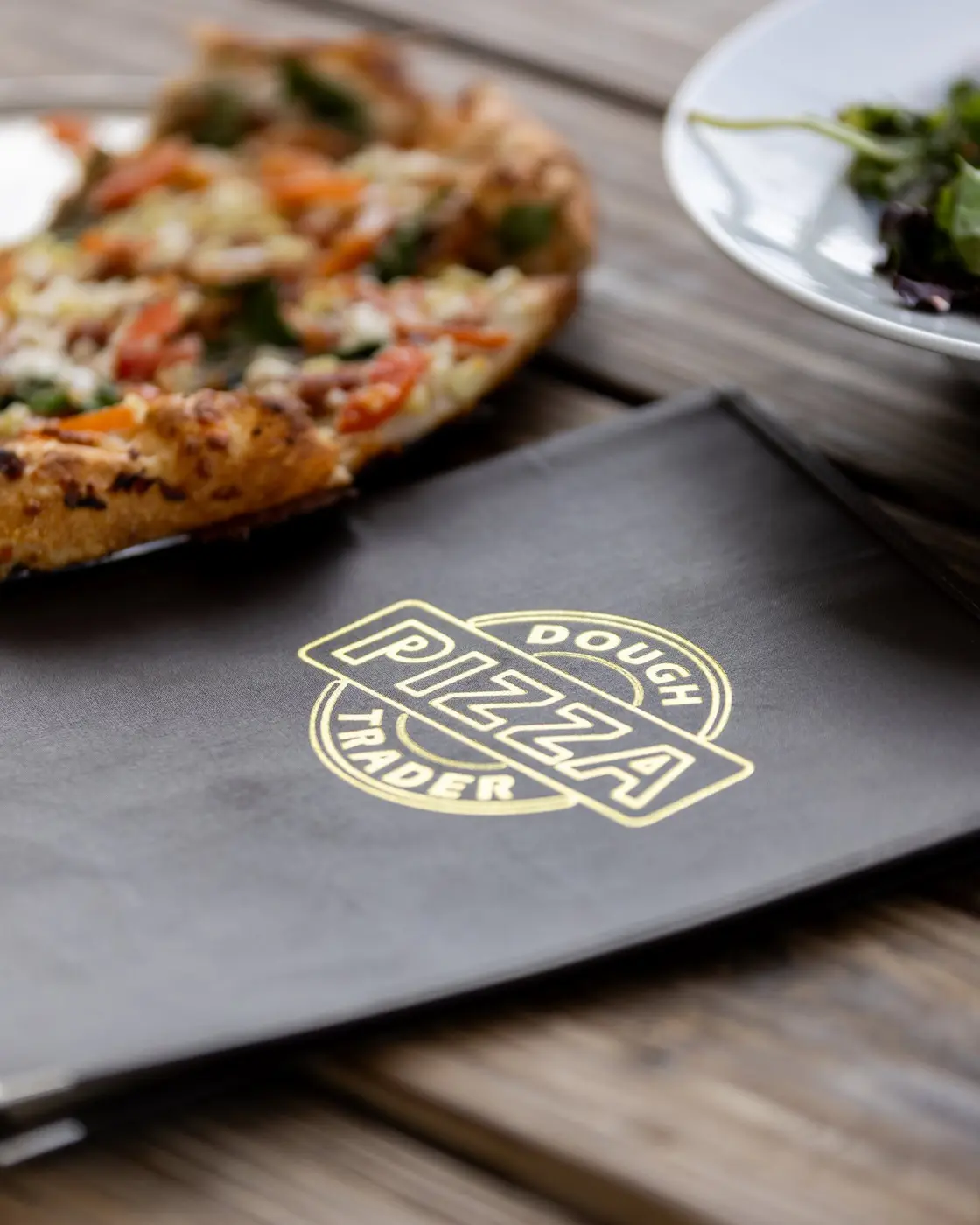 A Dough Trader menu beside pizza and salad