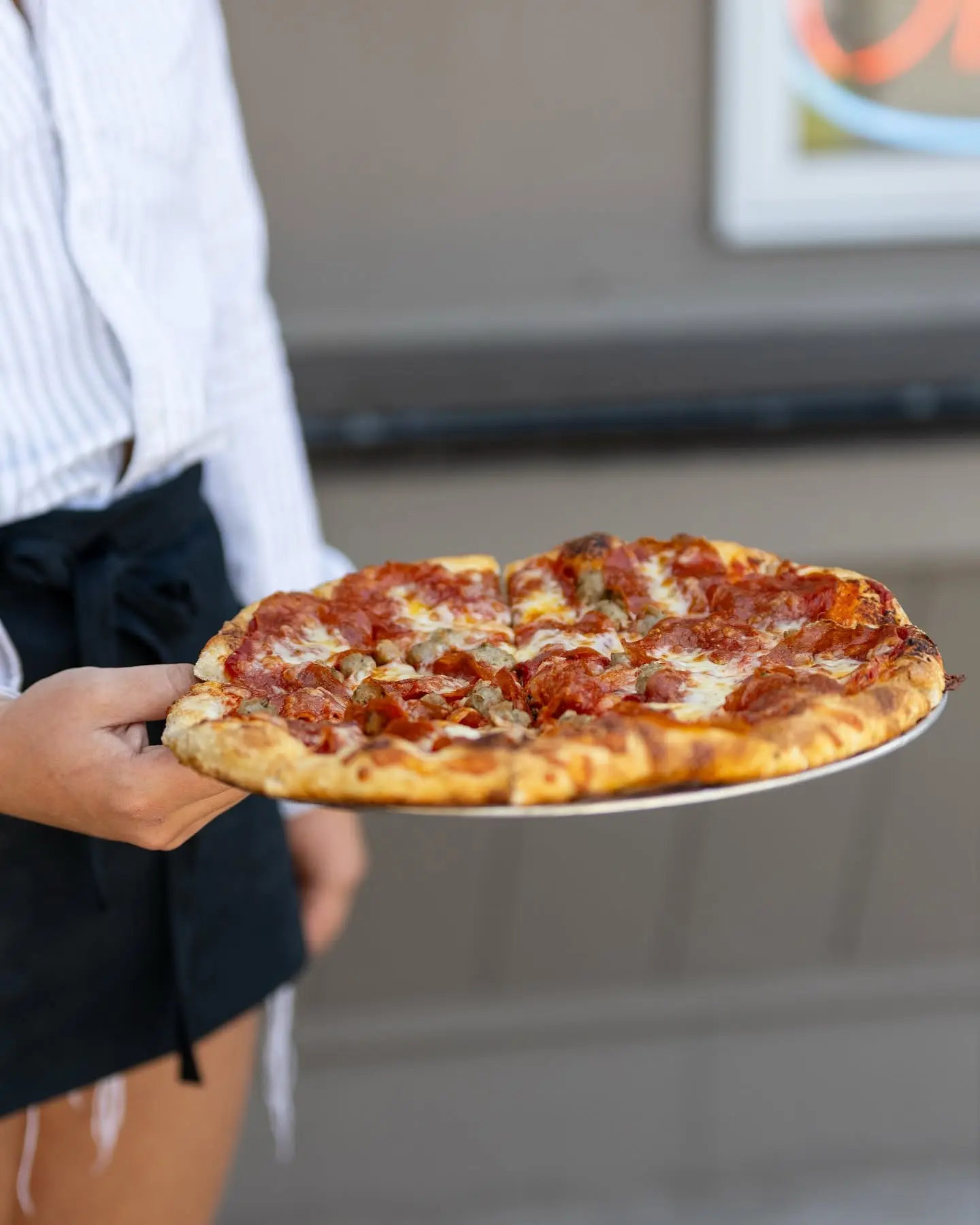 A Dough Trader team member presenting a fresh pizza